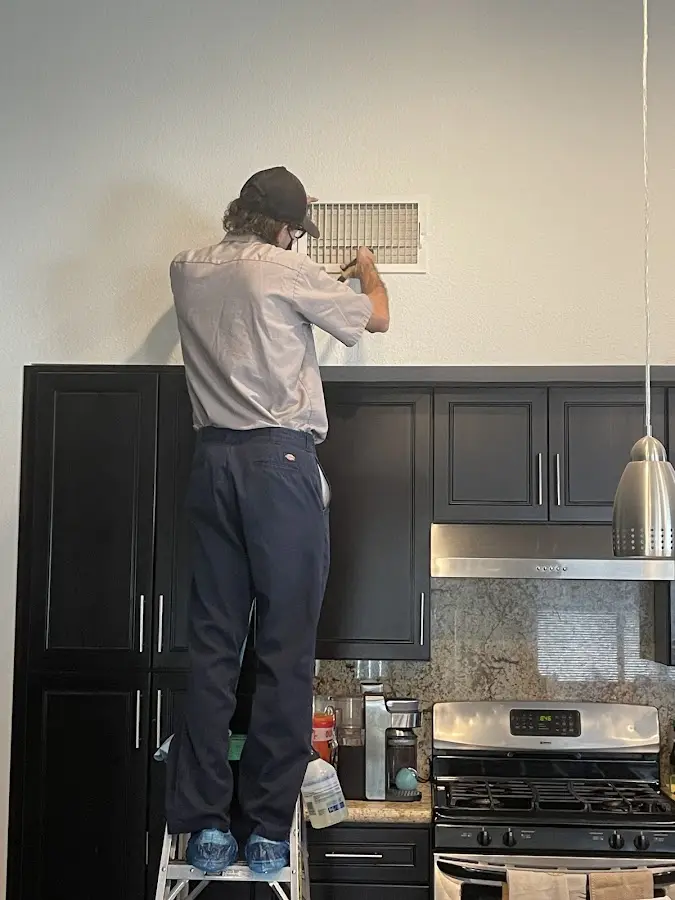 Technician inspecting an air vent during HVAC service in Aspen